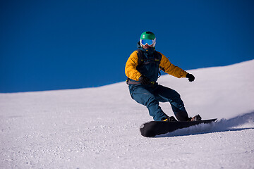 Image showing snowboarder running down the slope and ride free style