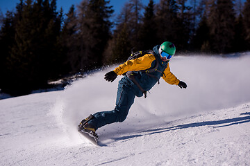 Image showing snowboarder running down the slope and ride free style