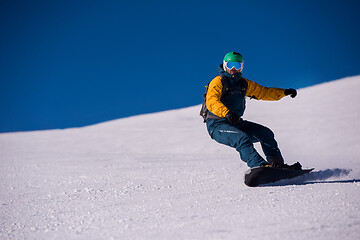 Image showing snowboarder running down the slope and ride free style