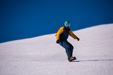 Image showing snowboarder running down the slope and ride free style