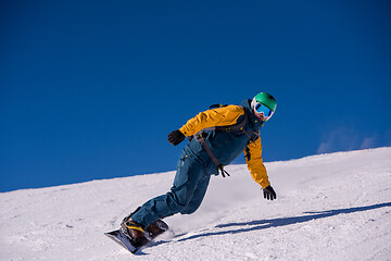 Image showing snowboarder running down the slope and ride free style