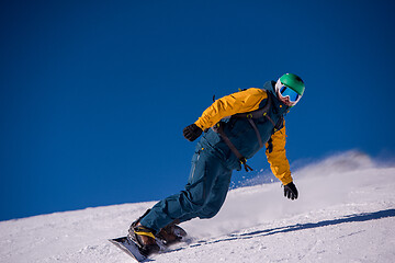 Image showing snowboarder running down the slope and ride free style