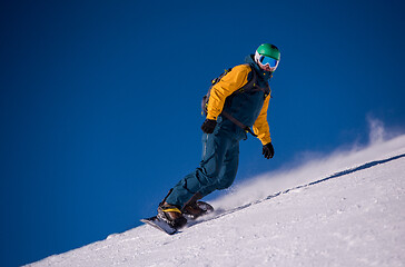 Image showing snowboarder running down the slope and ride free style