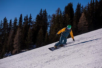 Image showing snowboarder running down the slope and ride free style