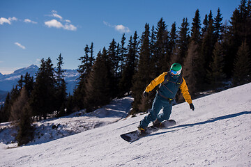 Image showing snowboarder running down the slope and ride free style