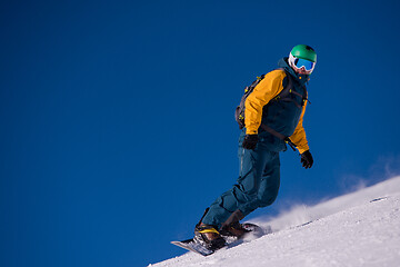 Image showing snowboarder running down the slope and ride free style