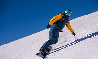 Image showing snowboarder running down the slope and ride free style