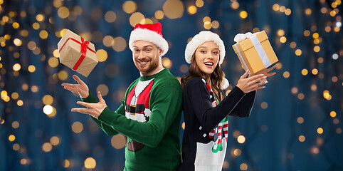 Image showing happy couple in christmas sweaters with gifts