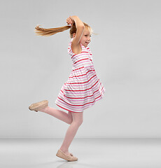 Image showing happy little girl in striped dress jumping