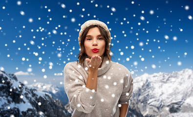 Image showing young woman in knitted winter hat sending air kiss