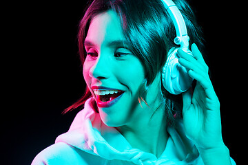 Image showing woman in headphones listening to music in neon