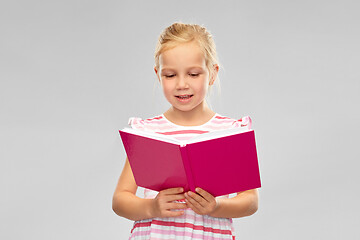 Image showing smiling little girl reading book