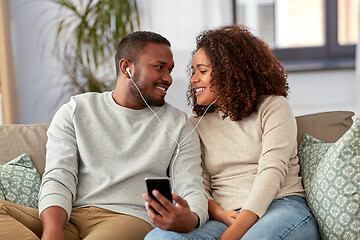 Image showing happy couple with smartphone and earphones at home