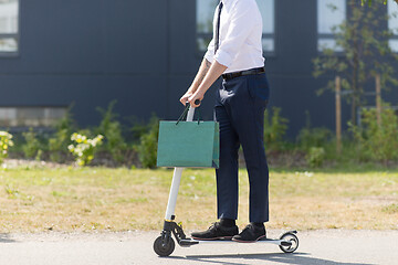 Image showing businessman with shopping bag riding scooter