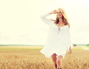 Image showing smiling young woman in white dress on cereal field