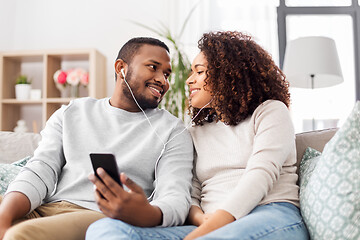 Image showing happy couple with smartphone and earphones at home