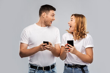 Image showing happy couple in white t-shirts with smartphones