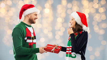 Image showing happy couple in christmas sweaters with gift box