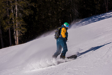 Image showing snowboarder running down the slope and ride free style