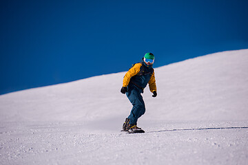 Image showing snowboarder running down the slope and ride free style