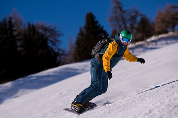 Image showing snowboarder running down the slope and ride free style