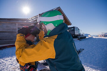 Image showing father preparing his little son for the first time on a snowboar