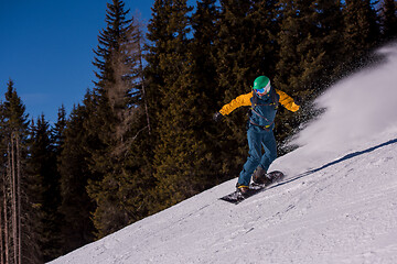 Image showing snowboarder running down the slope and ride free style