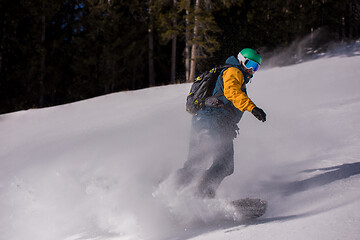 Image showing snowboarder running down the slope and ride free style