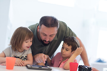 Image showing single father at home with two kids playing games on tablet