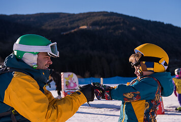 Image showing father preparing his little son for the first time on a snowboar