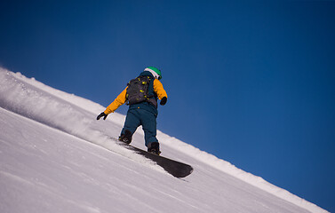 Image showing snowboarder running down the slope and ride free style