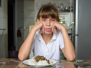 Image showing The girl refuses the food offered and shows her tongue