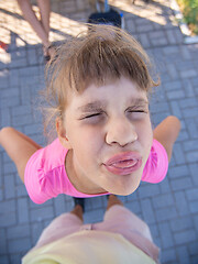 Image showing Mischievous girl grimaces and shows a vile muzzle with a tongue