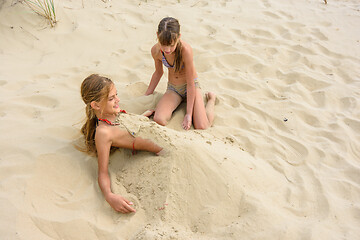 Image showing Girl bury her girlfriend with sand on the sandy beach