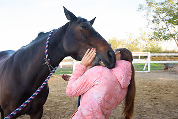 Image showing The horse tries to bite the girl on the shoulder