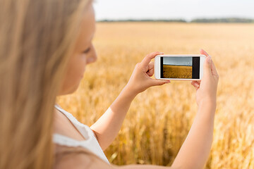 Image showing girl taking picture by smartphone on cereal field