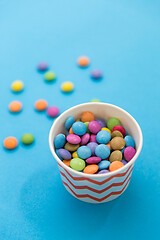 Image showing candy drops in paper cup on blue background