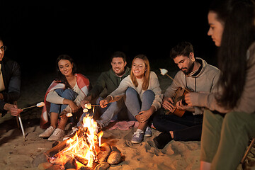 Image showing friends roasting marshmallow on camp fire on beach