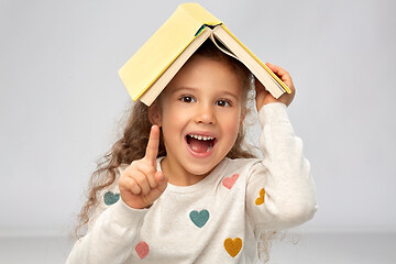 Image showing portrait of smiling girl with book on head