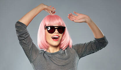 Image showing happy woman in pink wig and sunglasses dancing