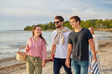 Image showing happy friends walking along summer beach