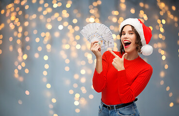 Image showing happy woman in santa hat with money on christmas