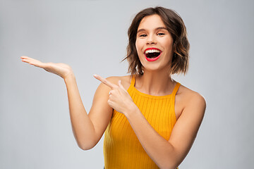 Image showing happy young woman holding something on empty hand