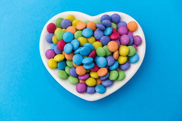 Image showing candies on heart shaped plate over blue background