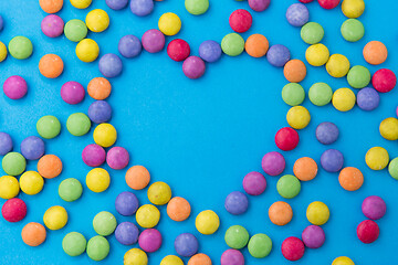 Image showing candy drops in shape of heart on blue background