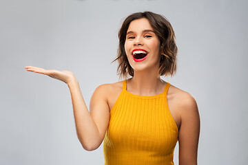 Image showing happy young woman holding something on empty hand