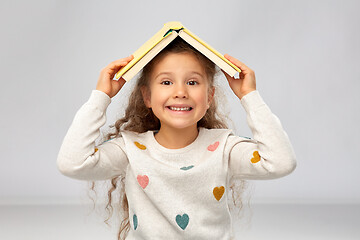 Image showing portrait of smiling girl with book on head