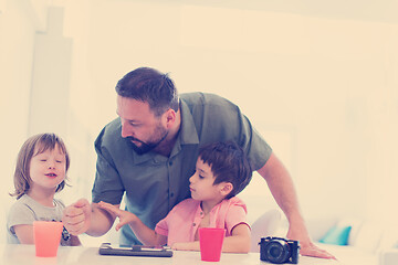 Image showing single father at home with two kids playing games on tablet