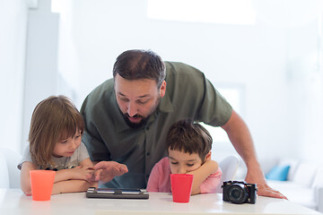 Image showing single father at home with two kids playing games on tablet