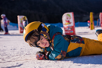 Image showing little snowboarder lying on the snow